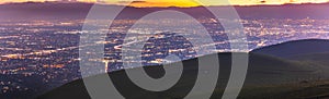 Panoramic night view of San Jose, Silicon Valley; the downtown area buildings visible on the right; green hills partially blocking