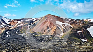 Panoramic over Landmannalaugar, Iceland, most colorful Brennisteinsalda Mount volcano and hikers at its top. Rough Icelandic