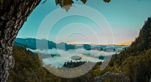 Panoramic photo of lake Bled island with church on a cold hazy foggy early autumn morning from Ojstrica vantage point. Visible