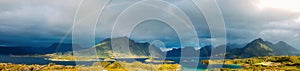 Panoramic photo of rainbow, sea, hills, blue sky in Norway on summer.