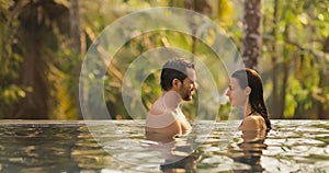 Couple in Love Together in Infinity Swimming Pool Outdoors During Tropical Vacation