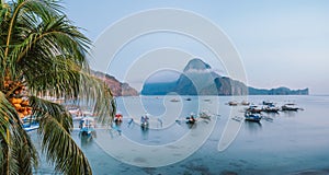 Panoramic scene of trip tourist boats in El Nido at evening sunset light. Palawan, Philippines. Cadlao island in