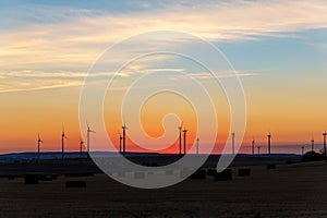 Panoramic scenic landscape view new modern wind turbine farm power generation station against fiery warm sunset sky