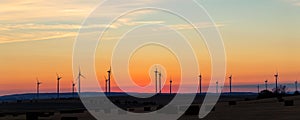 Panoramic scenic landscape view new modern wind turbine farm power generation station against fiery warm sunset sky