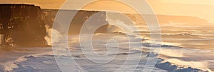 Panoramic seascape banner with ocean waves on shoreline crashing in rocks at sunrise