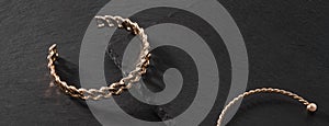 Panoramic shot of chain shape golden bracelet on black stone background with copy space