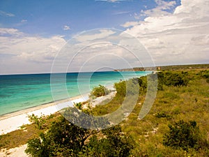 Panoramic shot of clear water of the sea on a white-sand shoreline