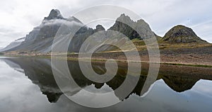 Panoramic shot of the Eystrahorn mountain chain with beautiful reflections in the water.