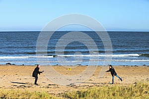 Panoramic shot of father and son playing flying disc on the beach of North Berwick a seaside town