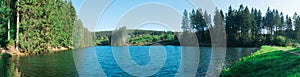 Panoramic shot of a forest lake with a forest on the shore on a fine autumn day under a blue sky