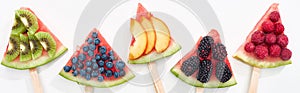 Panoramic shot of fresh watermelon on sticks with seasonal berries and fruits on white background.