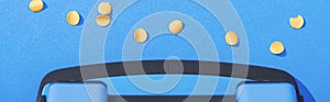 Panoramic shot of holepunch with paper circles on blue background.