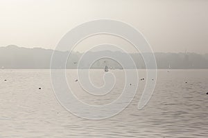 Panoramic shot of a lake with sailboats on a misty afternoon in Rotterdam