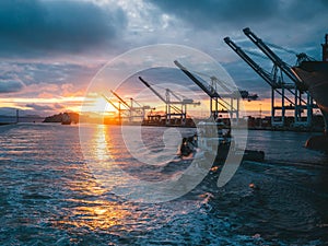 Panoramic shot of oil rigs at sea with a beautiful sunset in the background, under cloudy sky