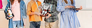 Panoramic shot of schoolkids holding robots