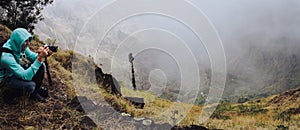 Panoramic shot of traveler making photo of amazing steep mountainous terrain with lush canyon valley on the path from Xo