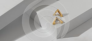 Panoramic shot of triangle golden earrings on geometric white background
