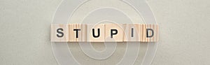 Panoramic shot of wooden blocks with stupid lettering on grey background, bullying concept.