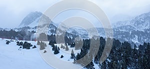 Panoramic snow mountain with fog and skiers descending the slope in the resort of Grandvalira, Pyrenees, Andorra.