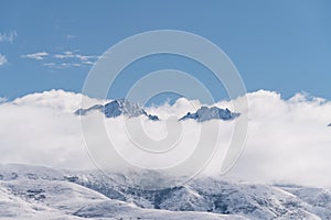 Panoramic snow mountains over white clouds and blue sky