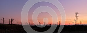 Panoramic sunset with the silhouettes of electric towers on the background