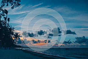 Panoramic sunset view of the tropical beach, ocean, and blue sky