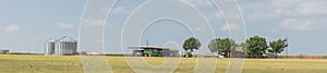 Panoramic Texas farm house with large storage tower silo in farmyard prairie