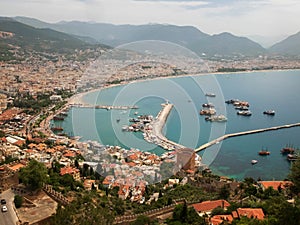 Panoramic view of Alanya, nautical vessels in the harbor, Kizil Kule tower and mountains. Alanya, Antalya, Turkey