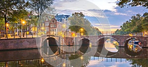 Panoramic view of Amsterdam at dawn. Downtownr. The lanterns are still on, but the sun has already colored the sky in multi-