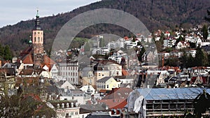 Panoramic view of Baden-Baden city with buildings with tiled roofs between mountains in spring sunny day. Baden