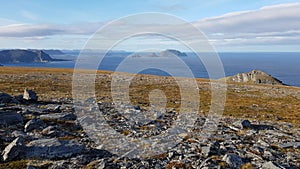 Panoramic view of barren landscape with bird island out in the blue sea, northcape county, northern Norway