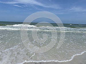 The panoramic view of the beach in clean, clear water and blue skies