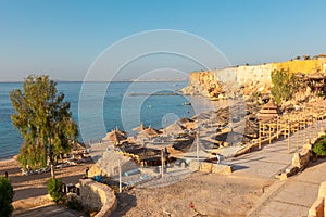 Panoramic view of beach Ras Umm El Sid. Beautiful sunrise over Red Sea with rocky shores, sandy beach with umbrellas and