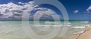 Panoramic view of a beautiful white sandy beach in the Caribbean Sea with beautiful turquoise colors under a blue sky.