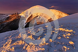 Panoramatický výhľad na nádhernú horskú scenériu zimnej ríše divov vo večernom svetle pri západe slnka. Hory nad oblakmi.
