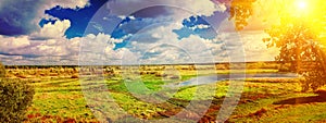 panoramic view on big meadow with small flood sky with sun instagram stile