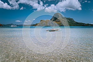 Panoramic view of blue lagoon with banca boat and Cadlao Island in background. Palawan, Philippines