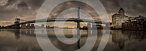 Panoramic view of Brooklyn Bridge against skyscrapers of New York on a gloomy day