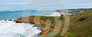 Panoramic view of California rugged Pacific ocean coastline with green hills near Pacifica during overcast winter day