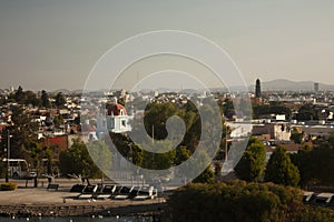 Panoramic view churches that mix between houses and buildings in the city of Puebla among trees Mexico