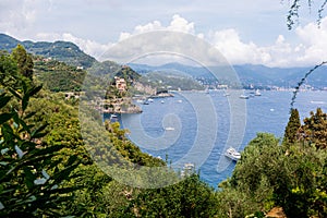 Panoramic view of the coast of Portofino and the Ligurian Sea in the Mediterranean. Trees and vegetation and some boats with photo