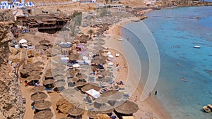 Panoramic view on coral beach with umbrellas, sunbeds and palms at the luxury hotel on Red Sea at Reef. Egypt.