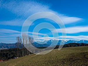 Hilly valley with high snowy Dachstein mountains on the horizon. Upper Austria.
