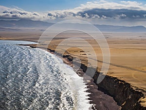 Panoramic view of the desert in Paracas National Reserve with the famous Red Beach in foreground, Ica region, Peru