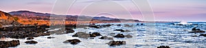 Panoramic view of the dramatic Pacific Ocean coastline at sunset, during low tide, Santa Cruz mountains in the background; San