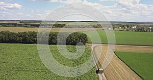 Panoramic view from drone above farming lands with moving truck along dirt road.