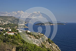 Panoramic view of Dubrovnikâ€™s coastline, with its clear blue waters and lush green cliffs, under a sky with clouds
