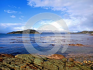 Panoramic view of extreme landscape of Argentine Patagonia. Snowy mountain ranges, frozen lake and rocks foreground under cloudy