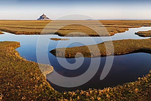 Panoramic view of famous historic Le Mont Saint-Michel tidal island on a sunny day with blue sky and clouds in summer, Normandy.