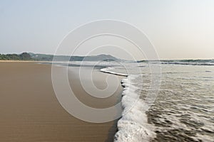 Panoramic view of foamy sea waves of Arabian Sea swashing on sandy Gokarna Main Beach, Karnataka, India